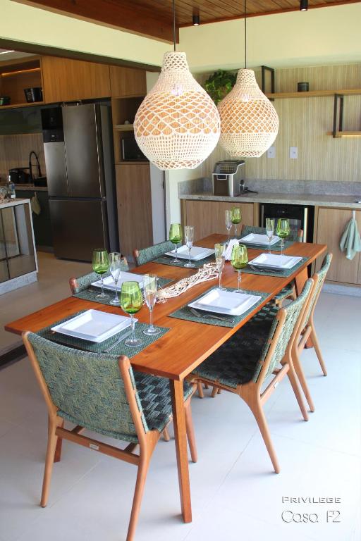 a wooden table with chairs and wine glasses at Exclusivo 2 suites a Beira Mar Imbassaí Privilege in Imbassai