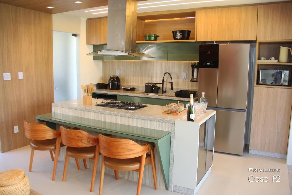 a kitchen with a counter with chairs and a refrigerator at Exclusivo 2 suites a Beira Mar Imbassaí Privilege in Imbassai