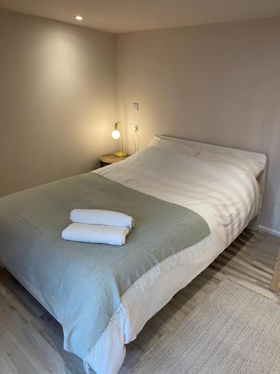 1 dormitorio con 1 cama con 2 toallas en El Nido - Self Catering cabin in Southbourne, 5 mins from beach en Iford