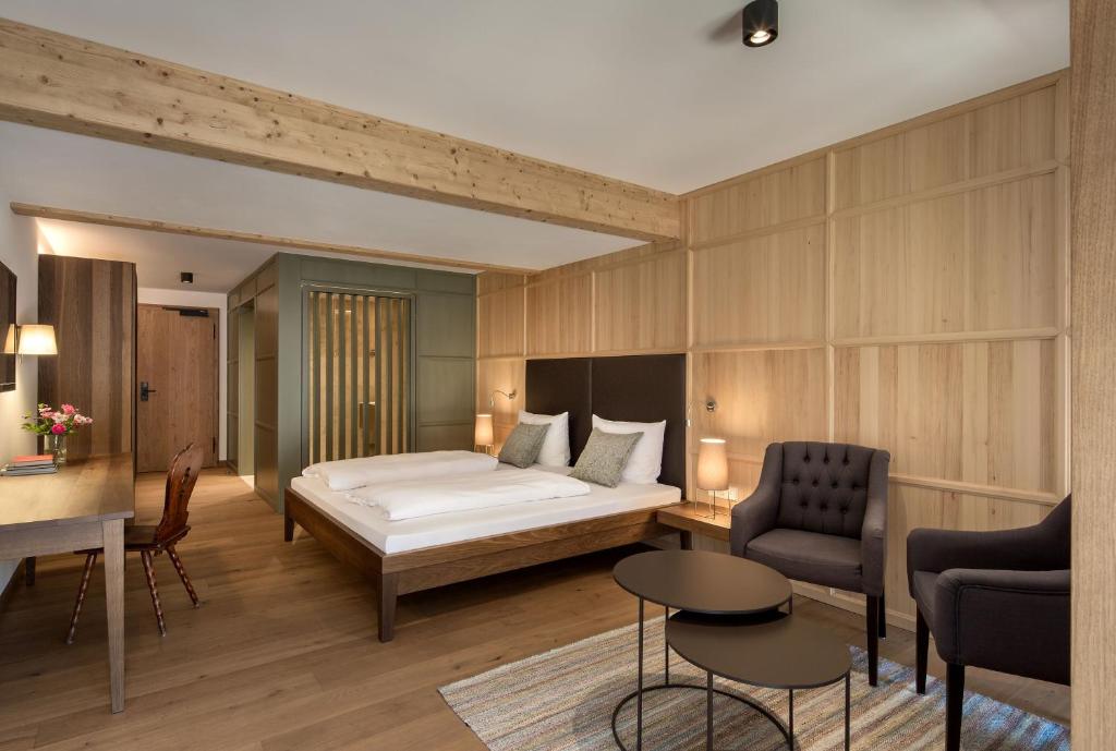 a bedroom with a bed and a desk and chairs at Gutshofhotel Winkler Bräu in Lengenfeld