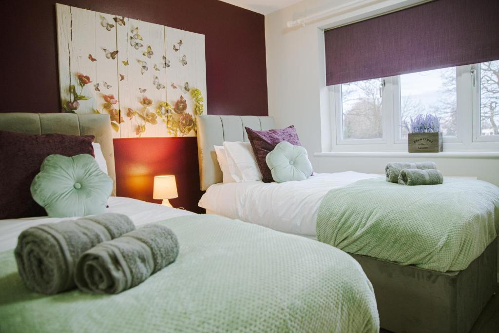 a bedroom with two beds with towels on them at Lovely Three Bed at Tanglewood in Hillingdon