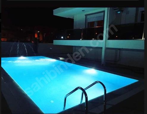 - une grande piscine éclairée en bleu la nuit dans l'établissement akdenız suıtes, à Altınkum