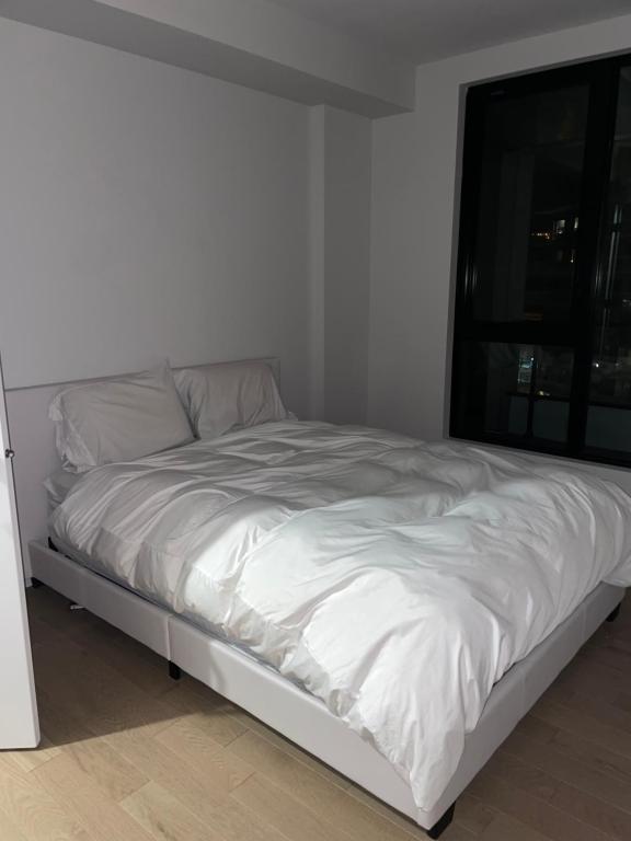 uma cama branca num quarto com uma janela em Stylist Apartment Heart of Brossard Dix30 em Brossard