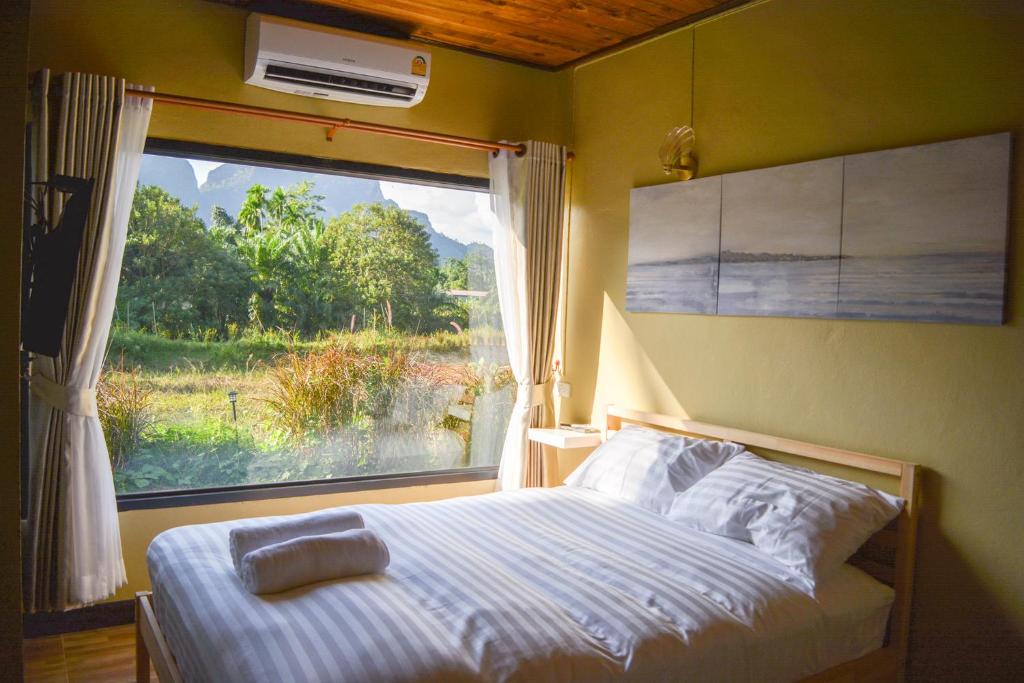 a bedroom with a bed and a window with a view at Phangnga Save House - เซฟเฮาส์พังงา in Phangnga