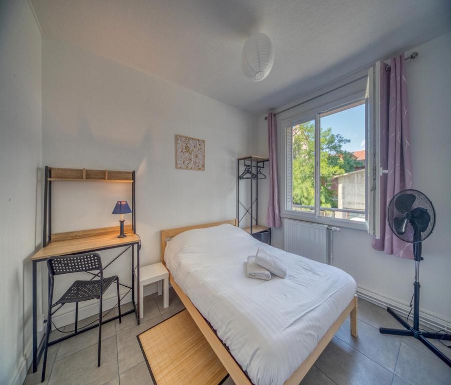 a bedroom with a bed and a desk and a window at Le théatre du Cours in Grenoble