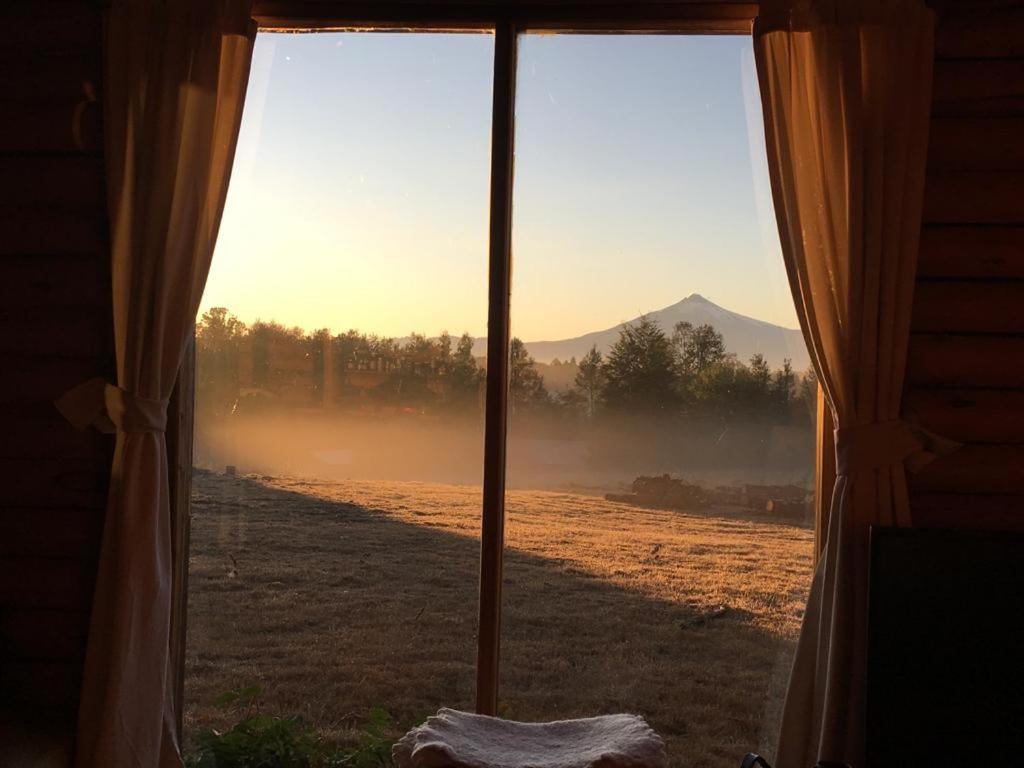 a window view of a field with a mountain view at Casa de Campo in Villarrica