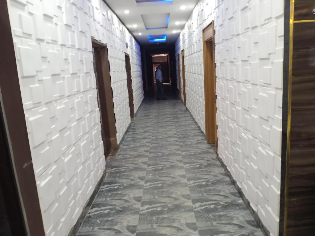 a hallway with white walls and a person walking down it at Givenchy Luxury Hotels and Suites in Awka