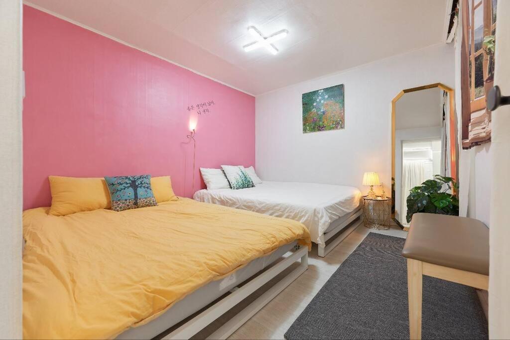 sypialnia z 2 łóżkami i różową ścianą w obiekcie Mapo Hongdae Detached Home w Seulu