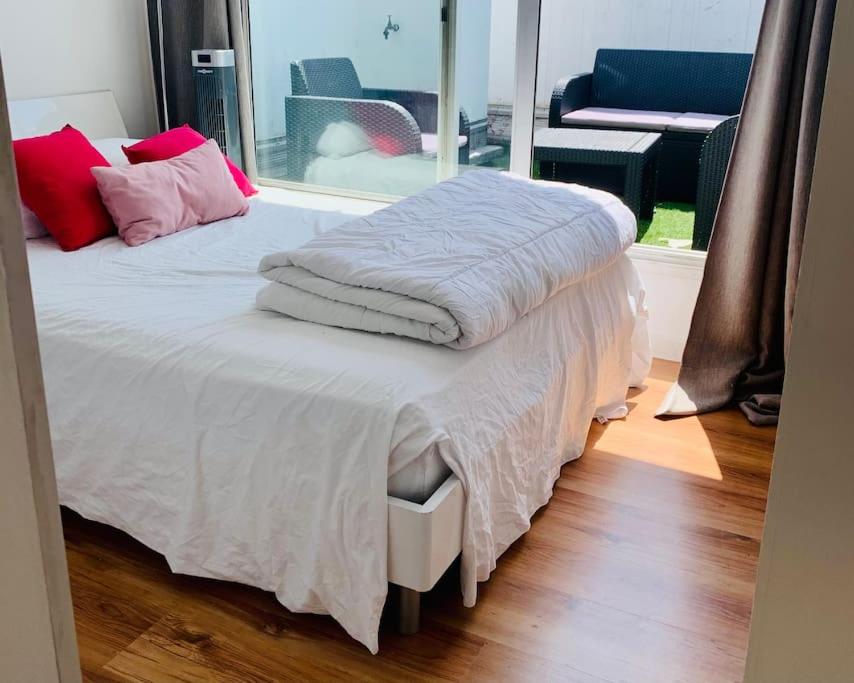 - un lit avec des draps blancs et des oreillers rouges dans l'établissement Duplex près des Champs-Élysées, à Paris