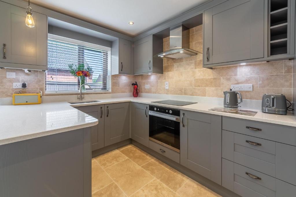 a kitchen with white cabinets and a window at One Lazy Duck in Heacham