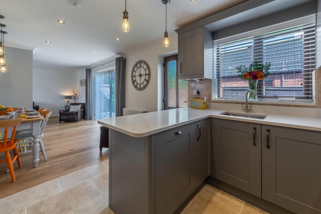 a kitchen with gray cabinets and a dining room with a table at One Lazy Duck in Heacham