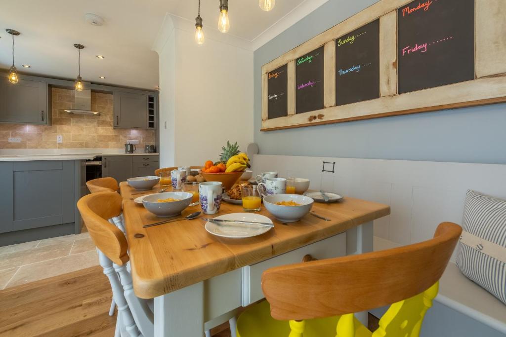 a kitchen with a wooden table with bowls of food on it at One Lazy Duck in Heacham