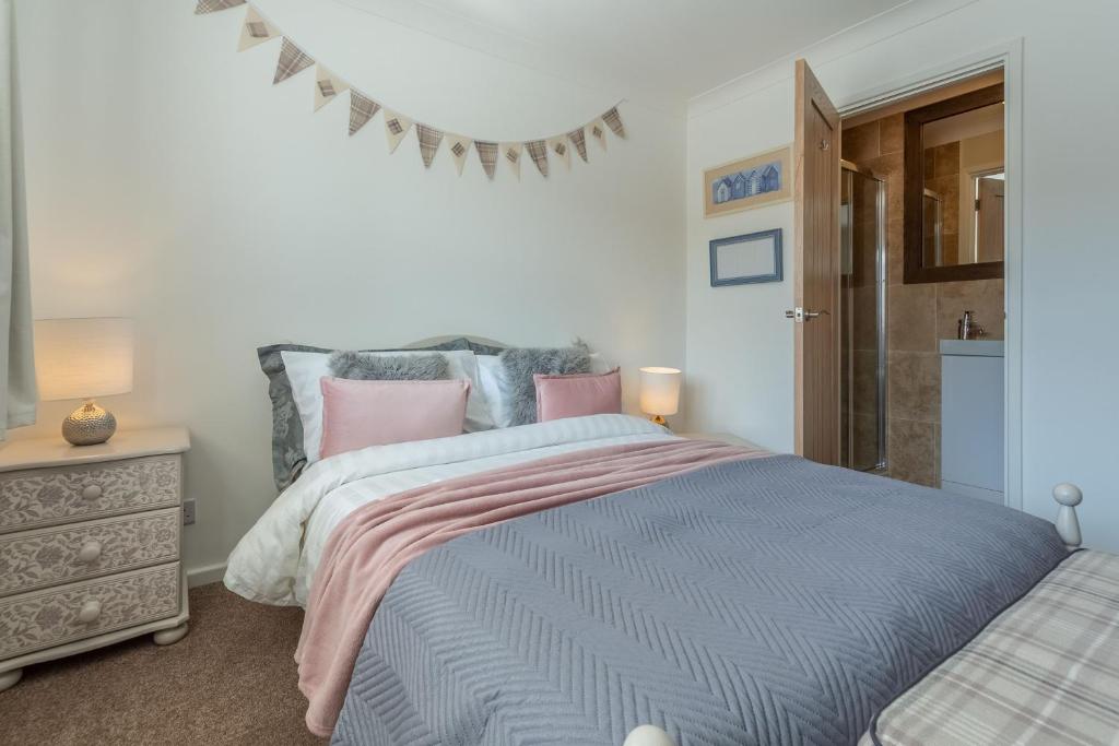 a bedroom with a large bed with pink and blue sheets at One Lazy Duck in Heacham