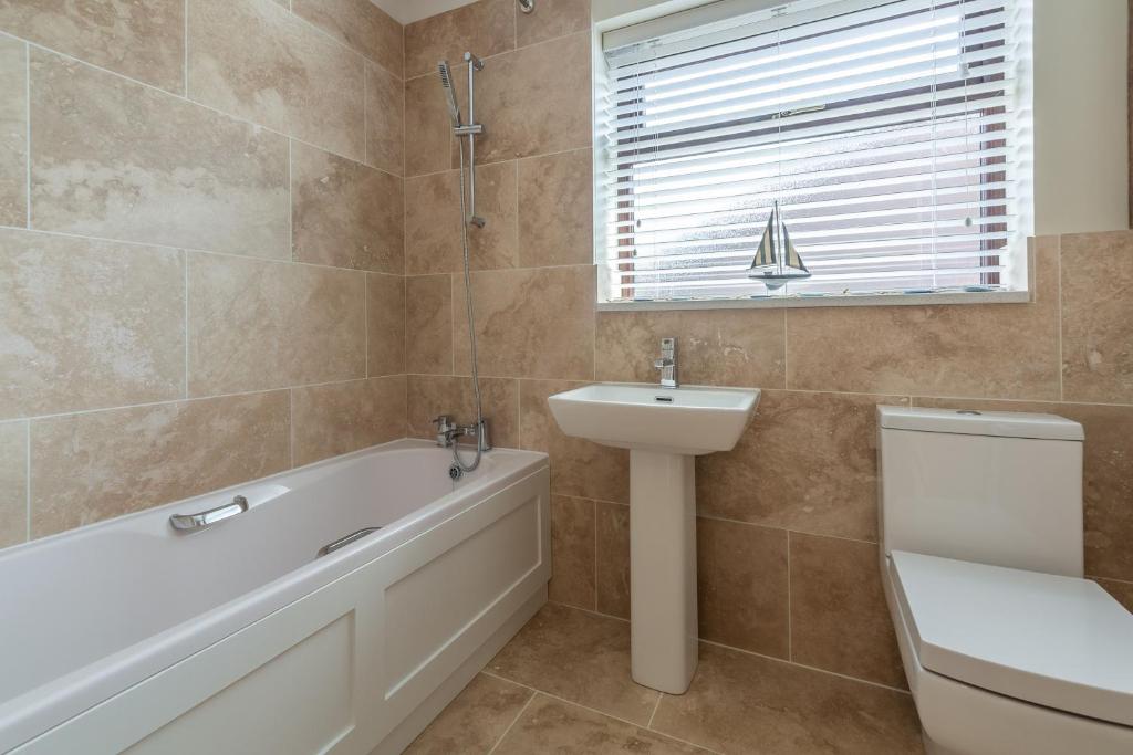 a bathroom with a tub and a sink and a toilet at One Lazy Duck in Heacham