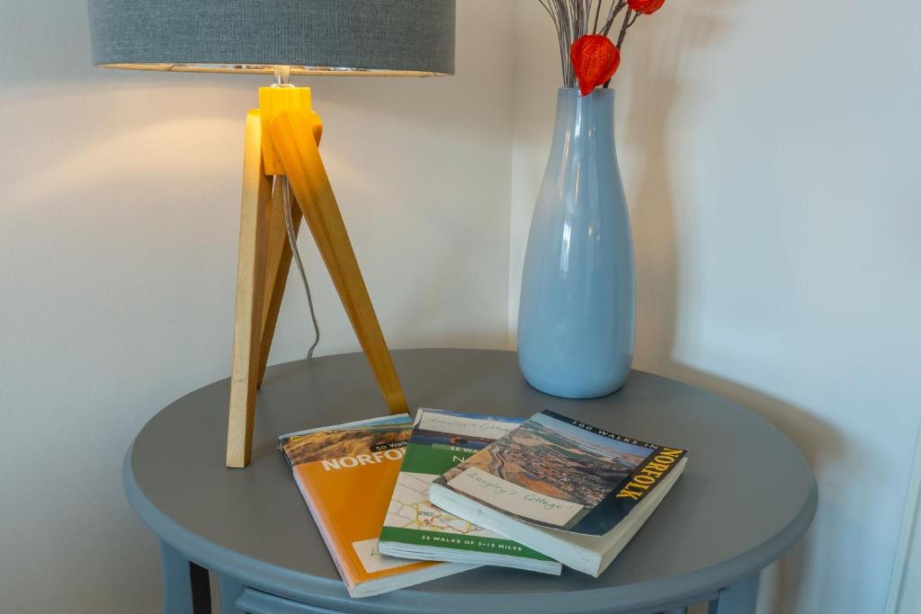 a table with books and a vase on it at One Lazy Duck in Heacham