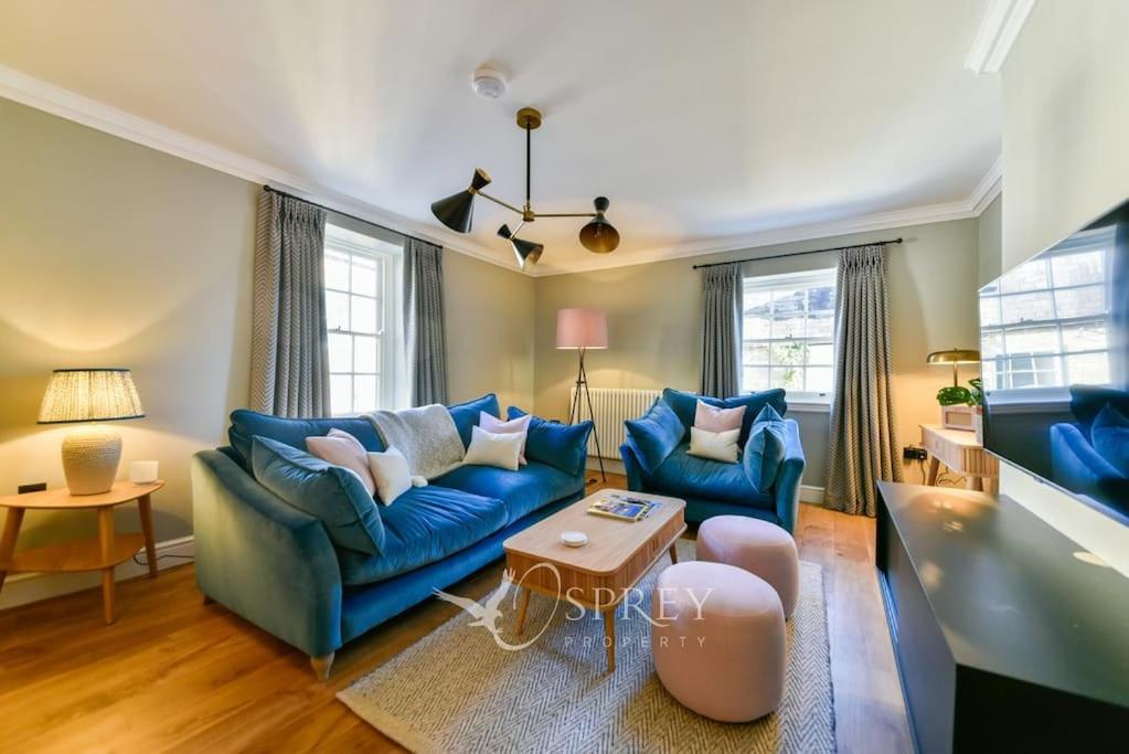uma sala de estar com dois sofás azuis e uma mesa em Church View em Oundle