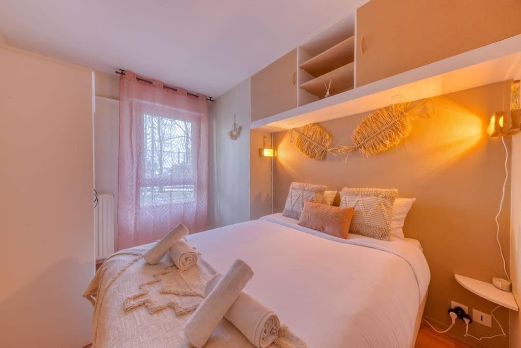 a bedroom with a large white bed and a window at La pépite bleue de Nanterre in Nanterre