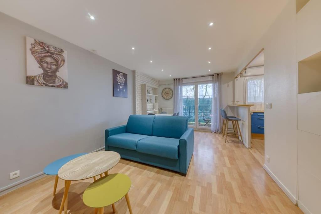 a living room with a blue couch and a table at La pépite bleue de Nanterre in Nanterre