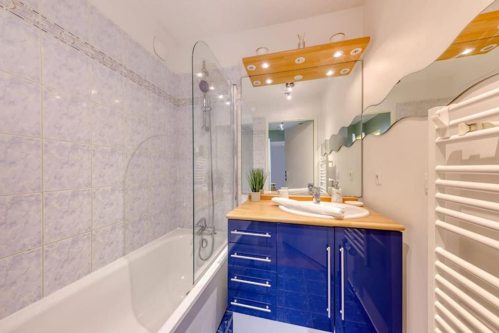 a bathroom with a sink and a shower and a tub at La pépite bleue de Nanterre in Nanterre