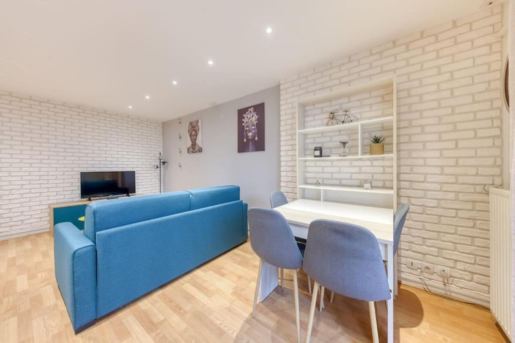 a living room with a blue couch and a table and chairs at La pépite bleue de Nanterre in Nanterre