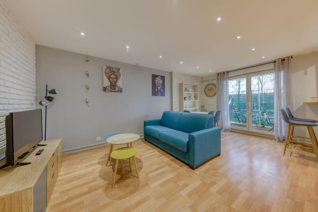 a living room with a blue couch and a tv at La pépite bleue de Nanterre in Nanterre