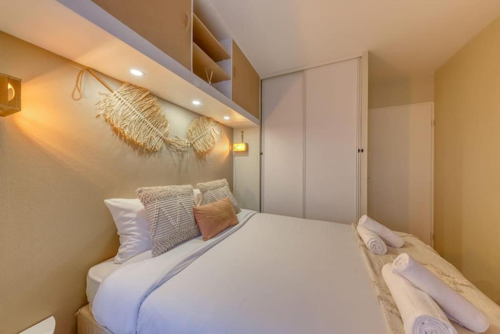 a small bedroom with a white bed with pillows at La pépite bleue de Nanterre in Nanterre