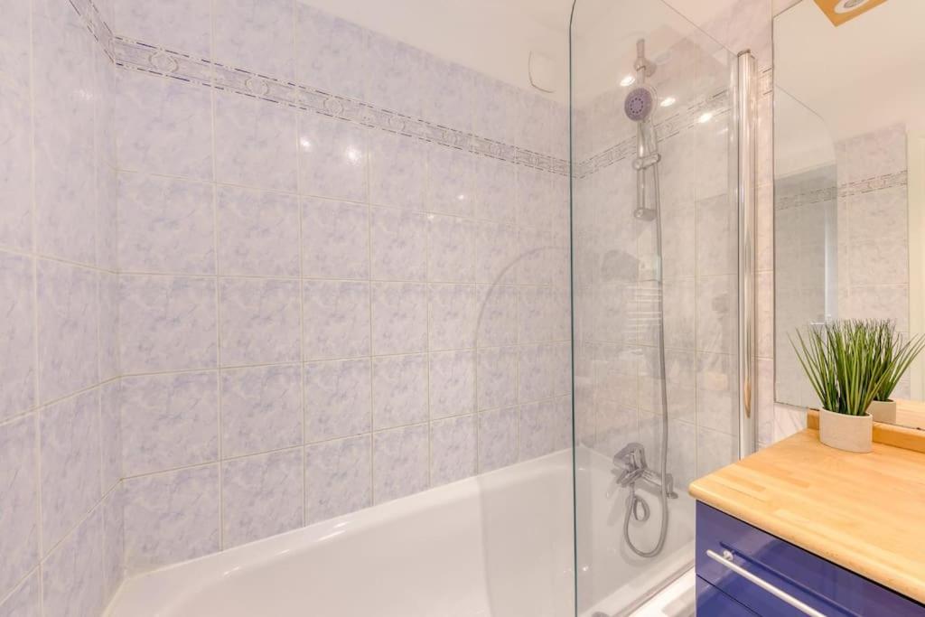 a bathroom with a tub and a shower with a glass door at La pépite bleue de Nanterre in Nanterre