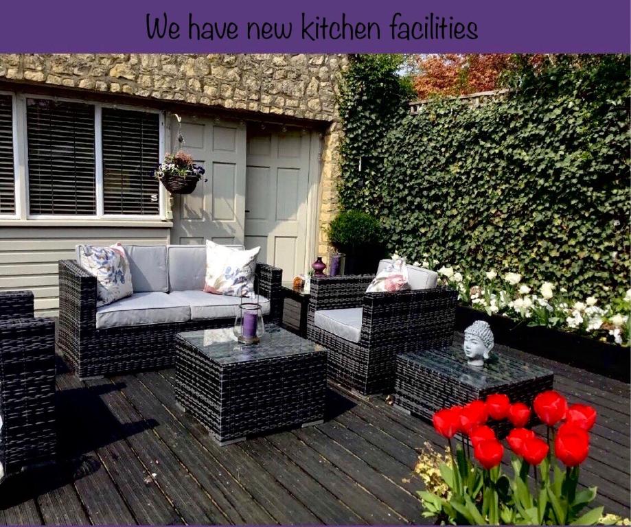 a patio with a couch and chairs and red flowers at THE HIDEAWAY - KENT in Sole Street