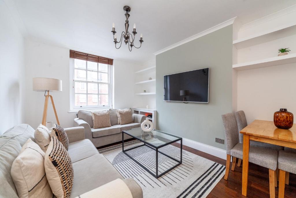 a living room with a couch and a tv at The St John's Wood Apartment in London