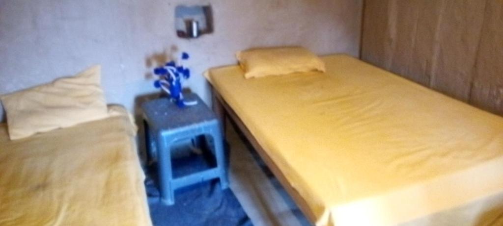 2 Betten in einem kleinen Zimmer mit einem Nachttisch und einem Tisch in der Unterkunft Shri Ram Homestay in Bangīna