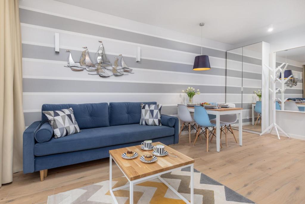 a living room with a blue couch and a table at Pobierowo Beach Baltic Apartments by Renters in Pobierowo