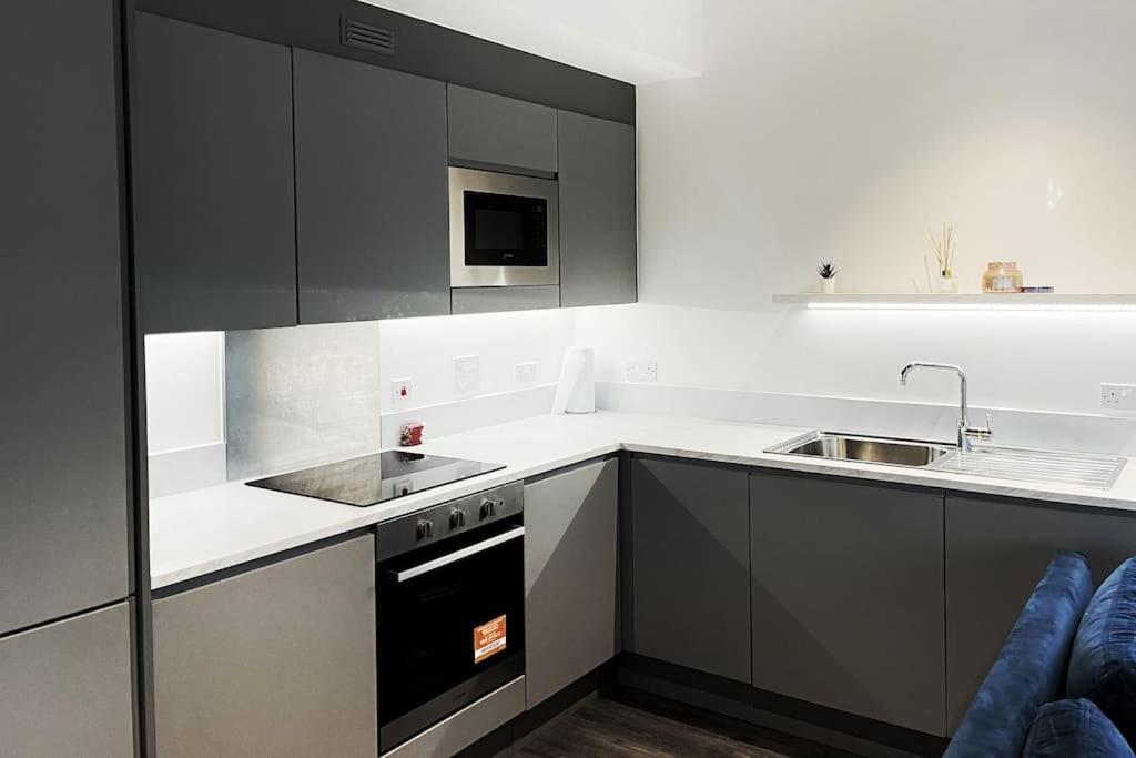 a kitchen with black and white cabinets and a sink at 2bed on Elizabeth line-5mins to Excel Custom House in London