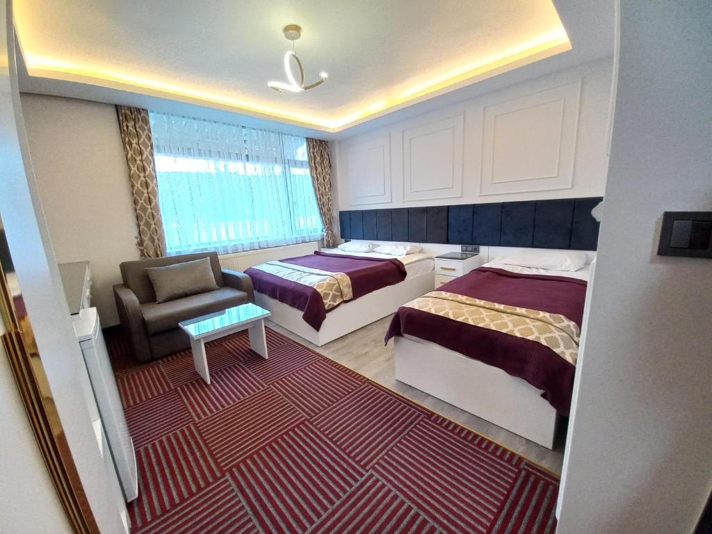 una camera d'albergo con due letti e una sedia di GRAND BELLİ OTEL a Altındağ