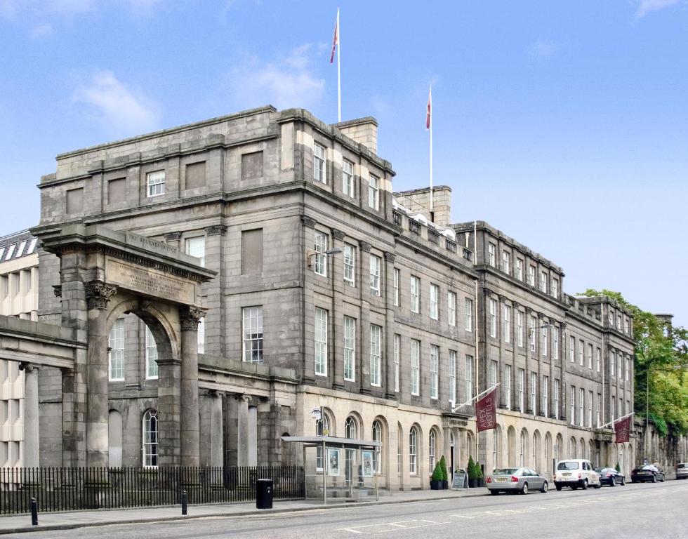 een groot stenen gebouw met twee vlaggen erop bij Apex Waterloo Place Hotel in Edinburgh