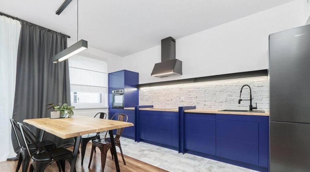 uma cozinha com armários azuis e uma mesa de madeira em Stylish Two-story Apartment - Nowy Oltaszyn em Iwiny
