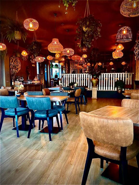 een restaurant met tafels en stoelen en kroonluchters bij Havenhotel At Sea Texel in Oudeschild