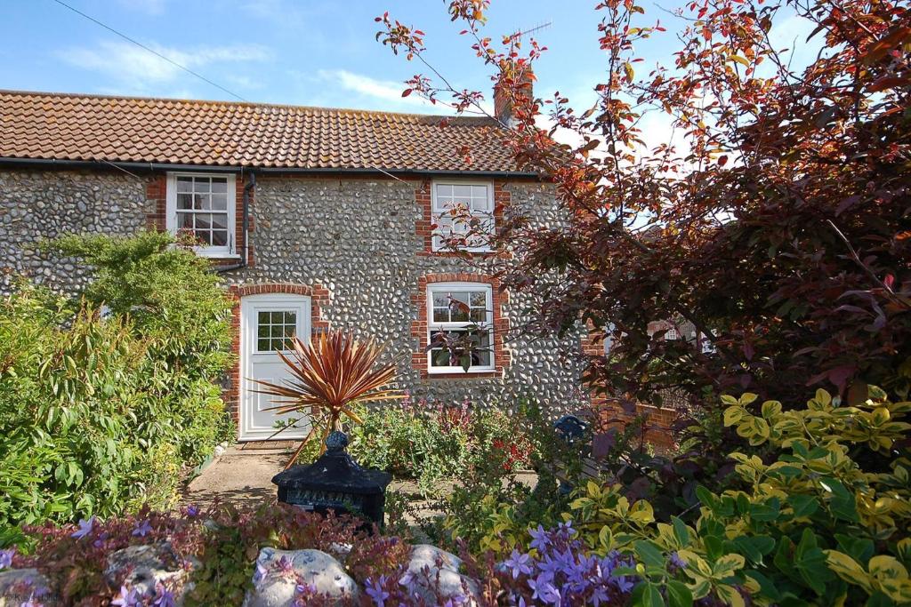 una casa de piedra con un jardín delante de ella en Romany Rye, en Sheringham
