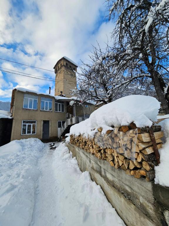 a stone wall covered in snow in front of a house at Guest House Ketevan Niguriani in Mestia