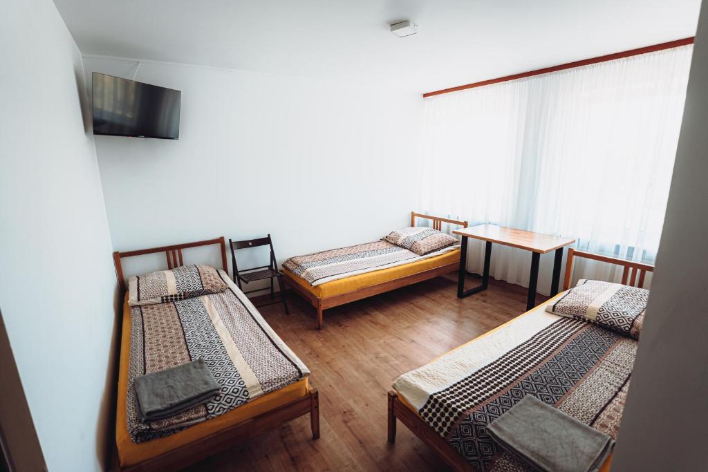 Cette chambre comprend 3 lits et une table. dans l'établissement Kalwados, à Radzymin