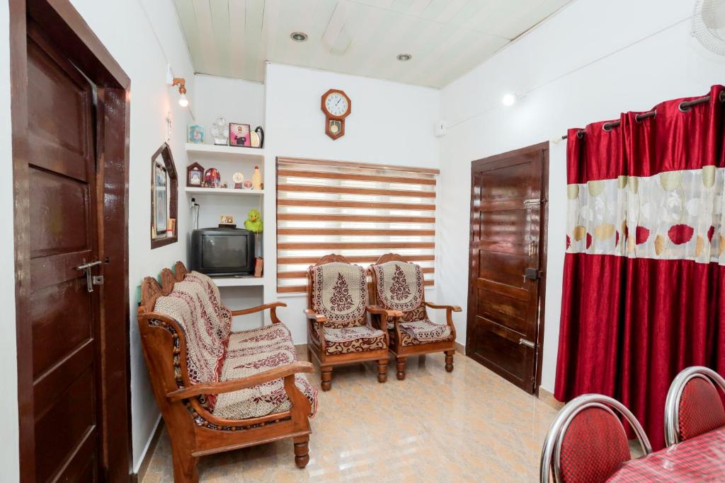 een woonkamer met stoelen en een televisie bij Koonamparayil Home Stay Munnar Anaviratty-Family Only in Anaviratty