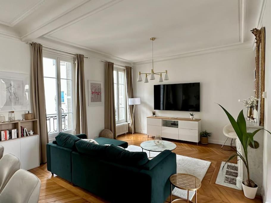 un salon avec un canapé bleu et une télévision dans l'établissement Splendide Appartement au coeur de St Germain / Odéon, à Paris