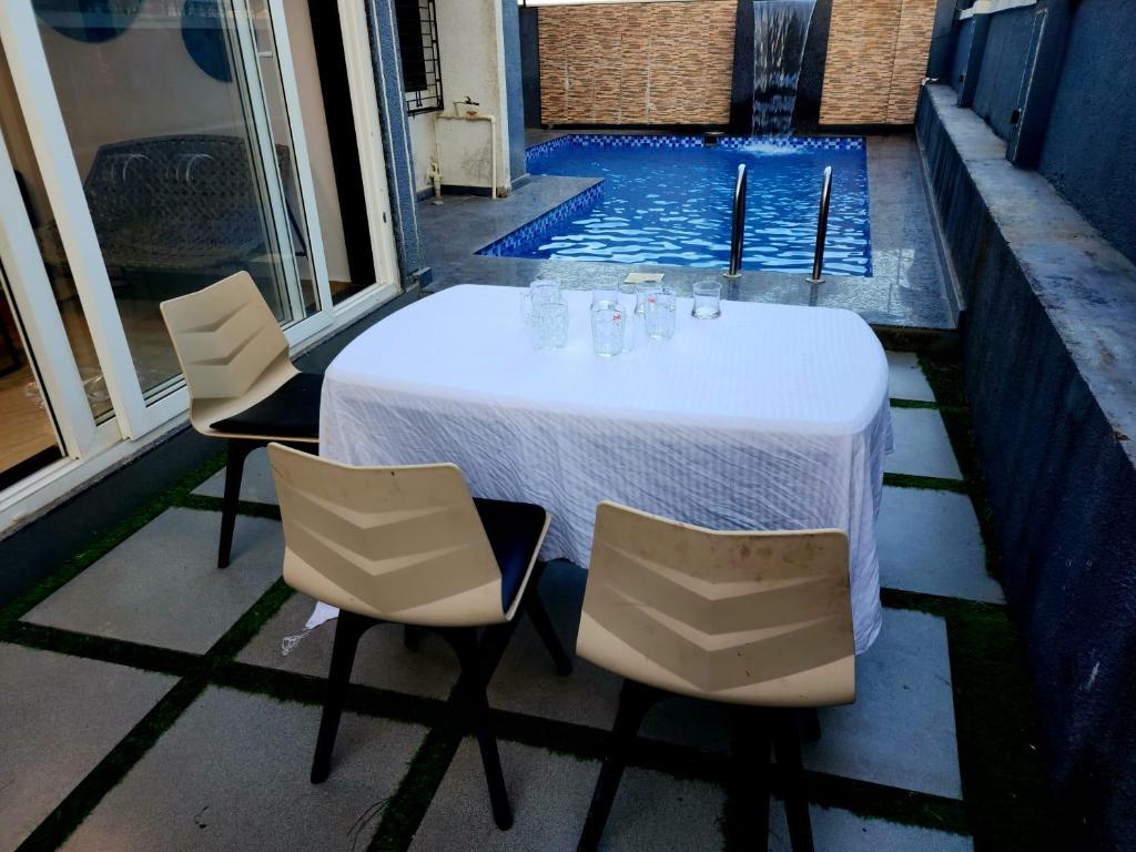 una mesa y sillas en un patio con piscina en ReUnion Villa ll Swimming Pool ll Snooker ll AC ll BBQ ll 3BHK, en Lonavala