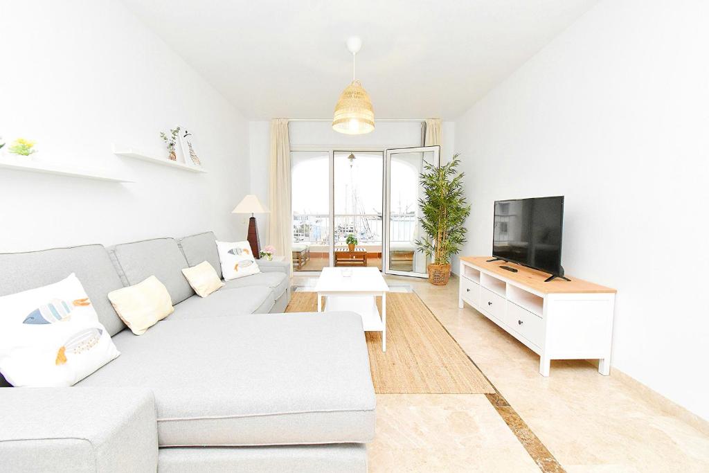 a white living room with a white couch and a tv at Expoholidays - Puerto Deportivo La Goleta in Almerimar