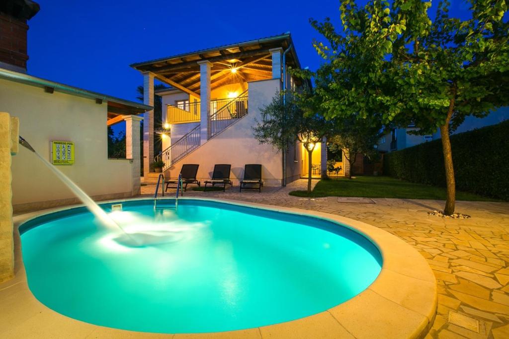 a swimming pool with a fountain in front of a house at Villa Cera Dignano in Vodnjan