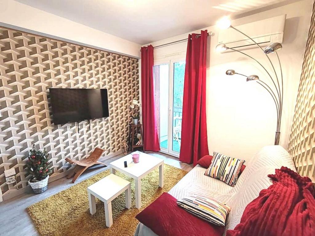 un salon avec un canapé et une télévision sur un mur dans l'établissement La Halte Catalane, à Perpignan