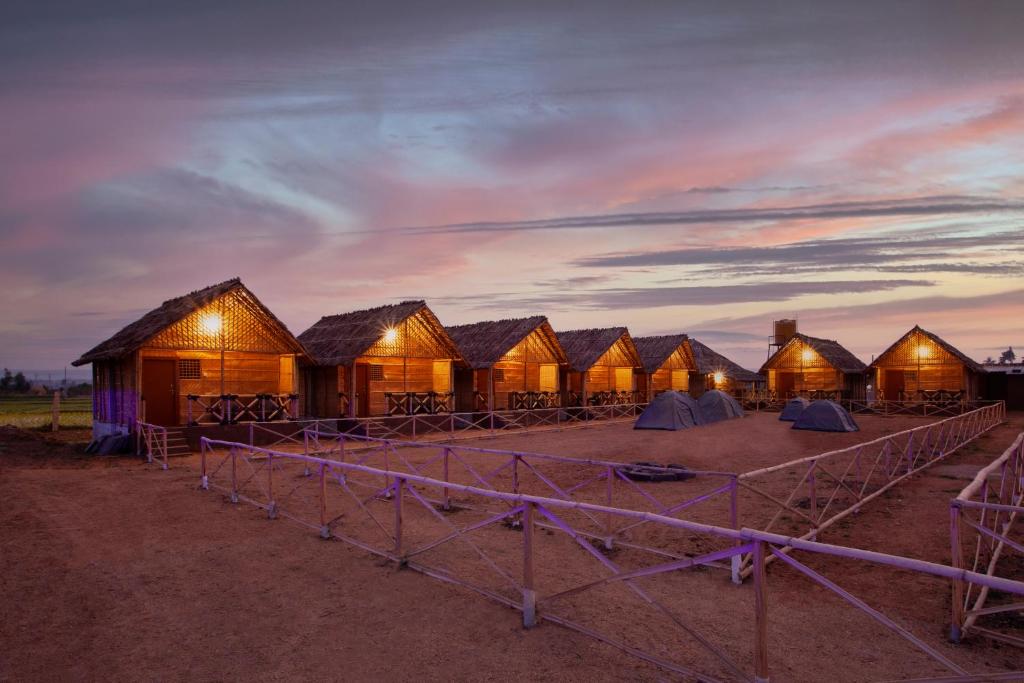a row of wooden huts in the desert at dusk at Hampi Social Resort in Hampi