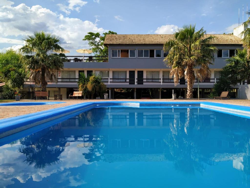 a swimming pool in front of a building with palm trees at Posada de Britopolis in Colonia Valdense