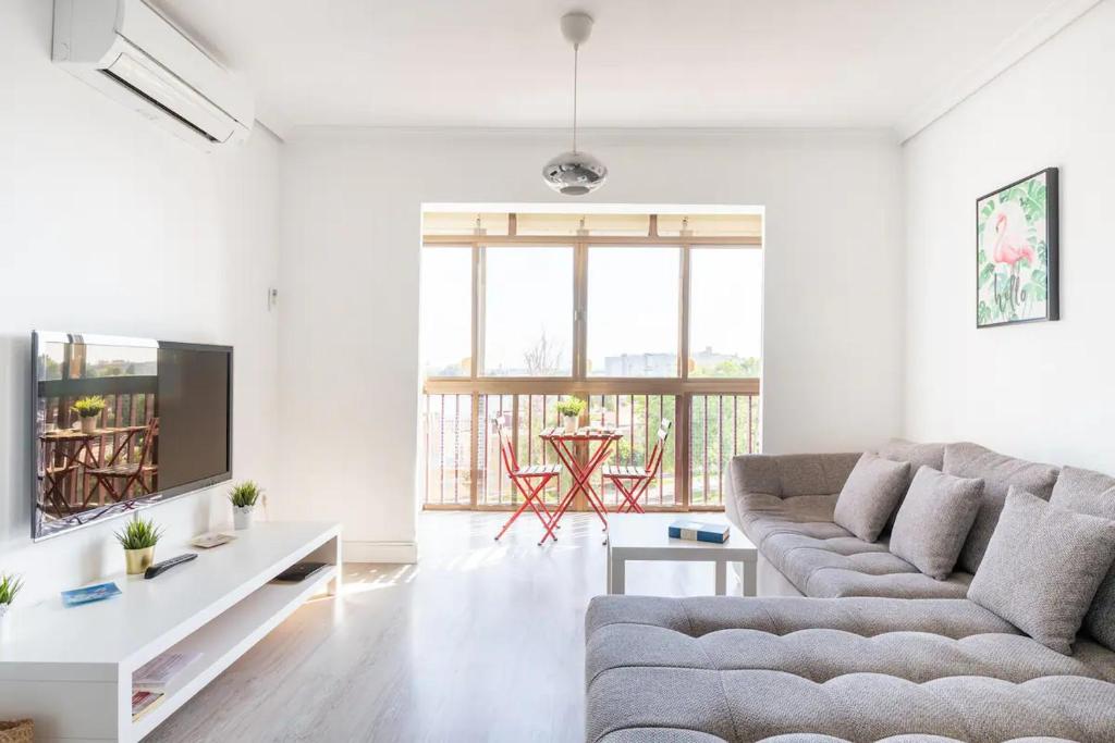 ein Wohnzimmer mit einem Sofa und einem TV in der Unterkunft Apartamento amplio con 4 habitaciones y 2 baños - Great apartment with 4 rooms - 2 baths in Sevilla