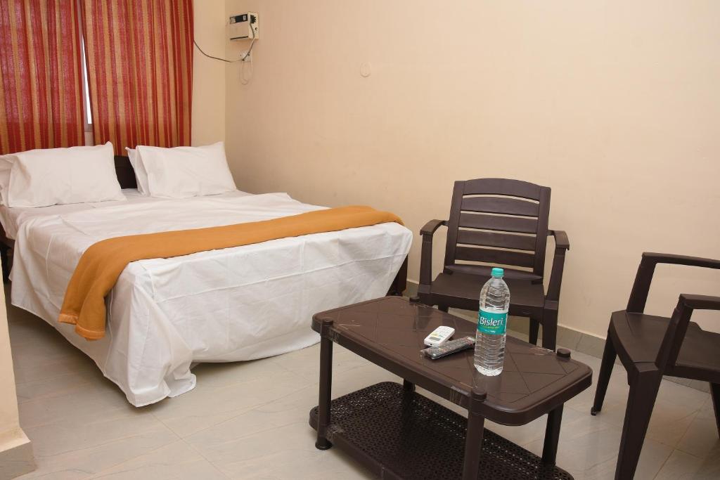 a bedroom with a bed and a table with a bottle of water at Hotel Park, Thiruvannamalai in Tiruvannāmalai