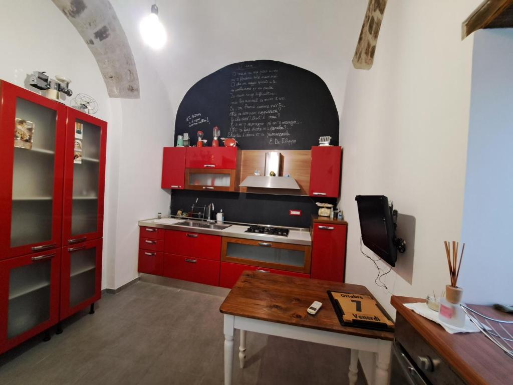 een keuken met rode kasten en een schoolbord aan de muur bij Carmela Camera&Comfort Monolocale in Caserta